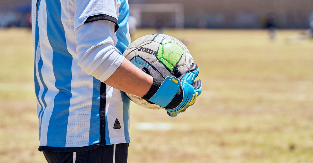 close-up of hands holding a football with a church building in the background