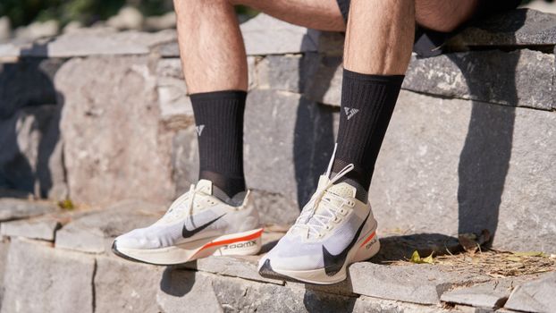 Close-up of running shoes and legs outdoors on stone steps, perfect for sport and lifestyle themes.
