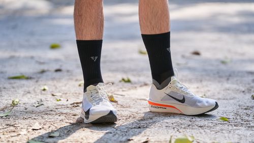 Free Close-up of running shoes and socks on a sunny outdoor path, featuring casual sportswear style. Stock Photo