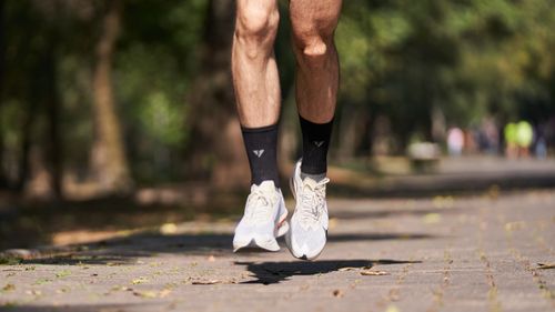 Free Close-up of a jogger's feet in mid-air on a sunny day in the park. Stock Photo