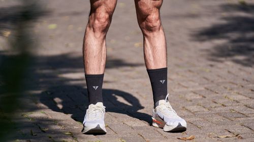 Free A runner's legs in shorts and sneakers on a sunlit stone pathway, perfect for fitness and outdoors themes. Stock Photo