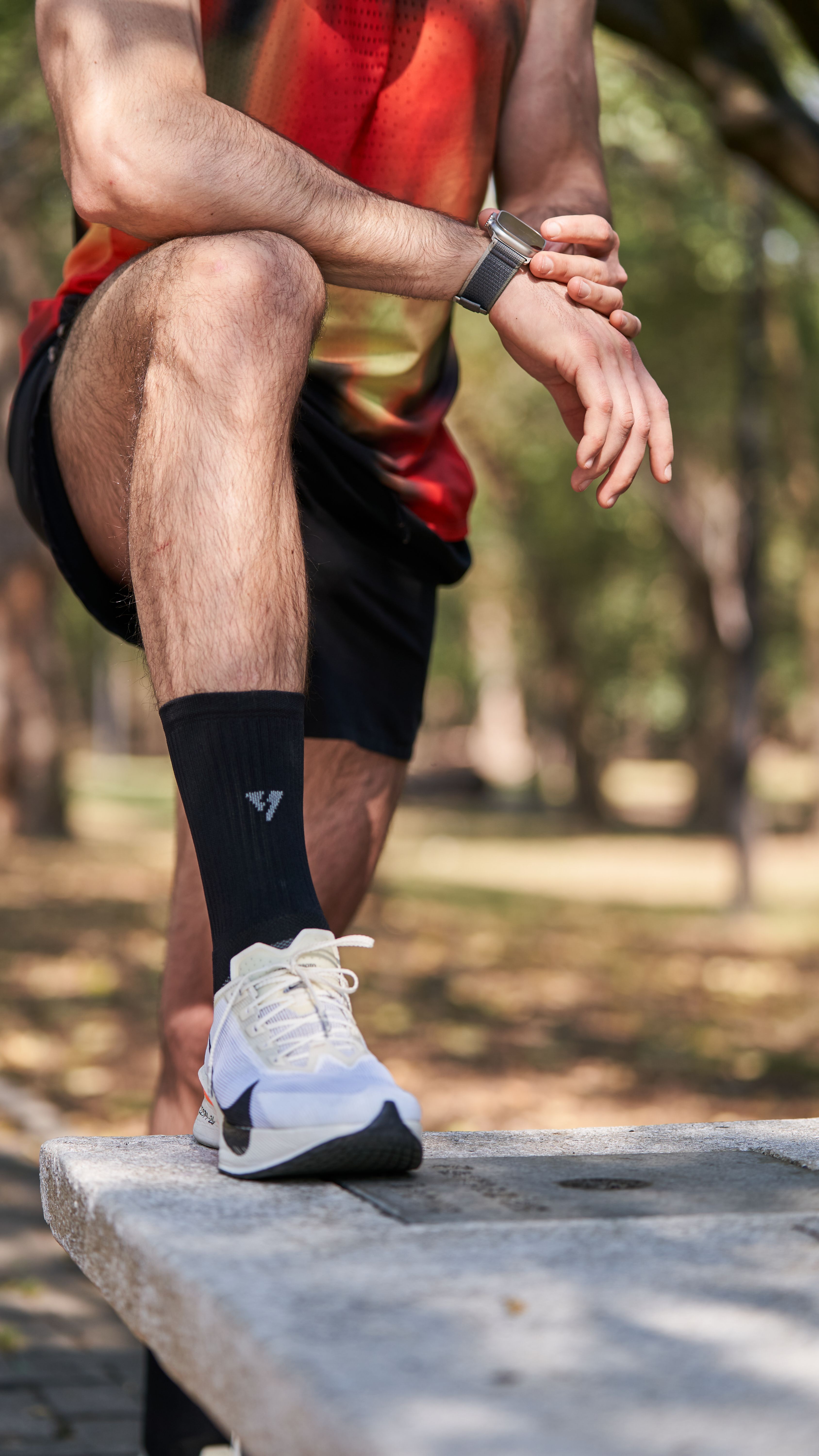 Close-up of an athlete resting on a park bench, emphasizing fitness gear and smartwatch.