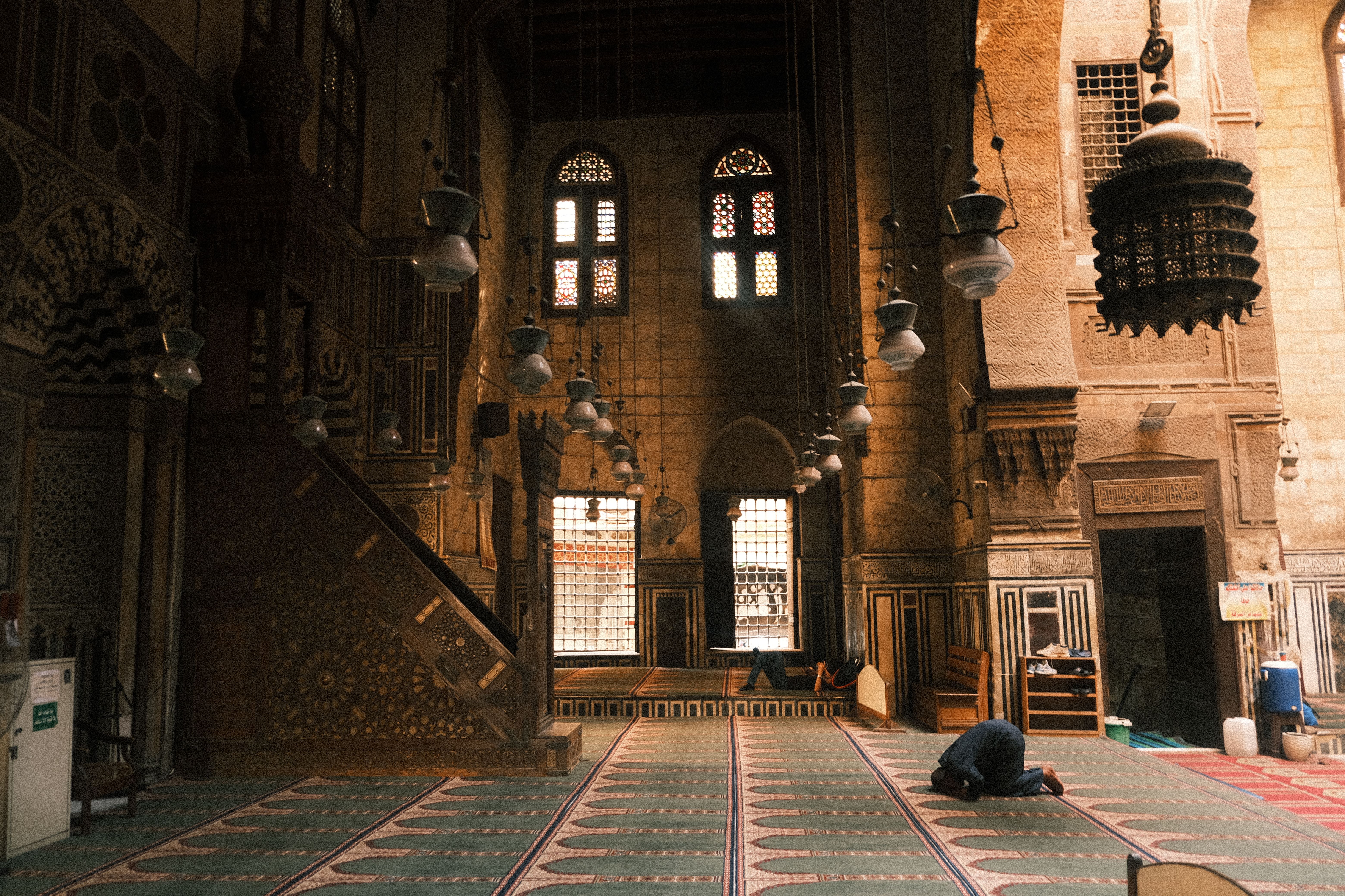 A serene moment inside a historic Egyptian mosque with a solitary figure praying.