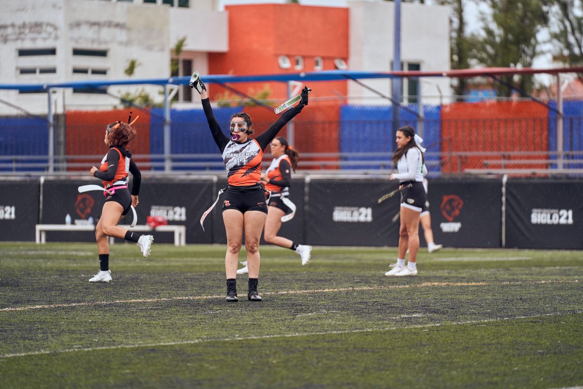 Female flag football players celebrating after a score on an outdoor field