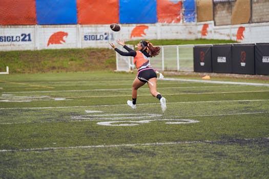 Young female athlete in action catching a football on a sports field.