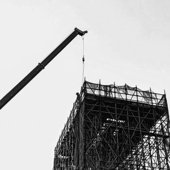 A dramatic black and white image of a construction crane and scaffold, highlighting industrial architecture.