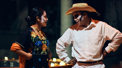 Free Two people dressed in traditional Day of the Dead attire with face paint engage in conversation. Stock Photo