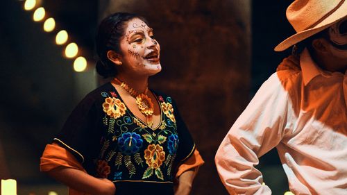 Free Colorful attire and face paint at an outdoor Day of the Dead celebration captured with night illumination. Stock Photo