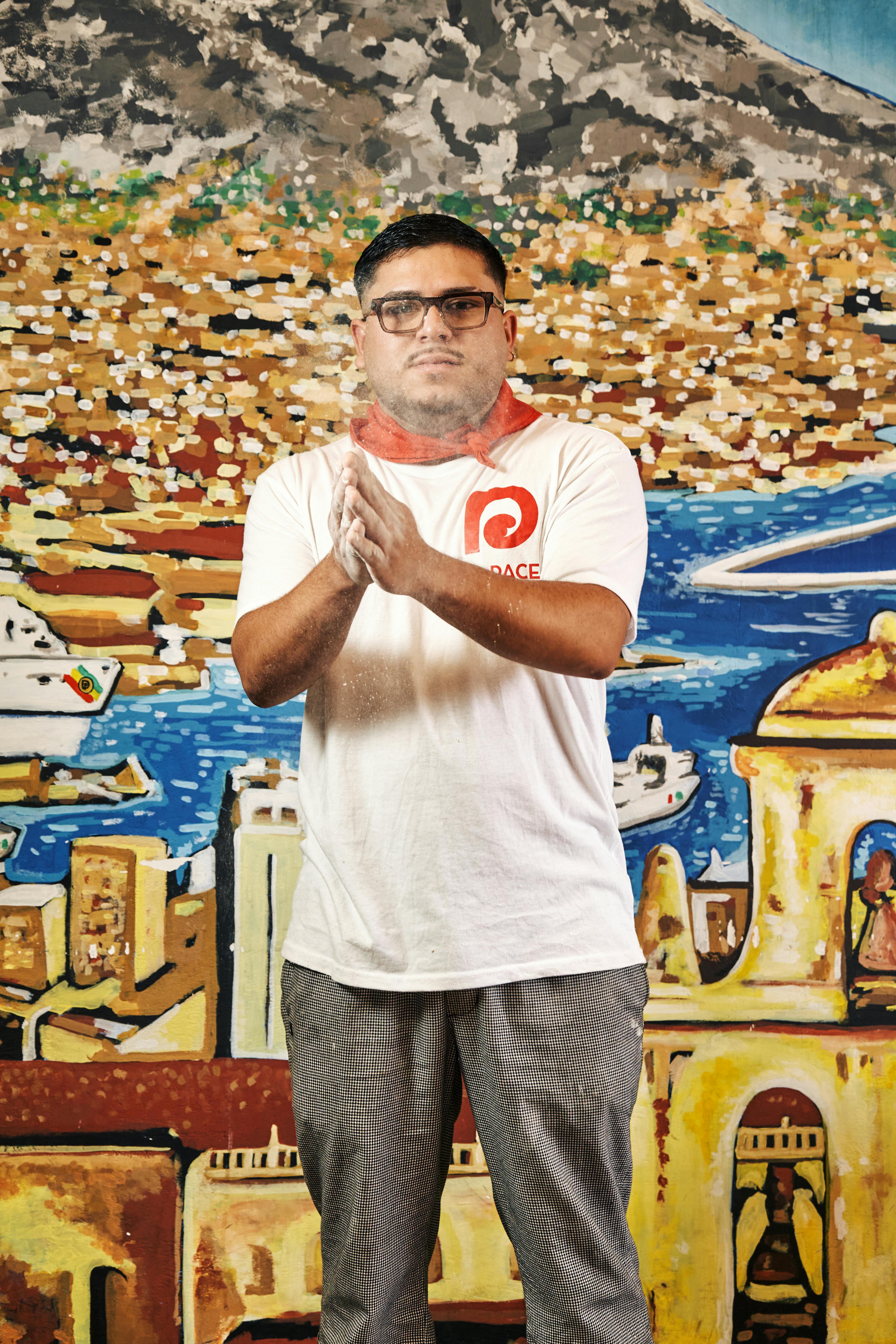 Man standing in front of a vibrant mural, clapping hands.