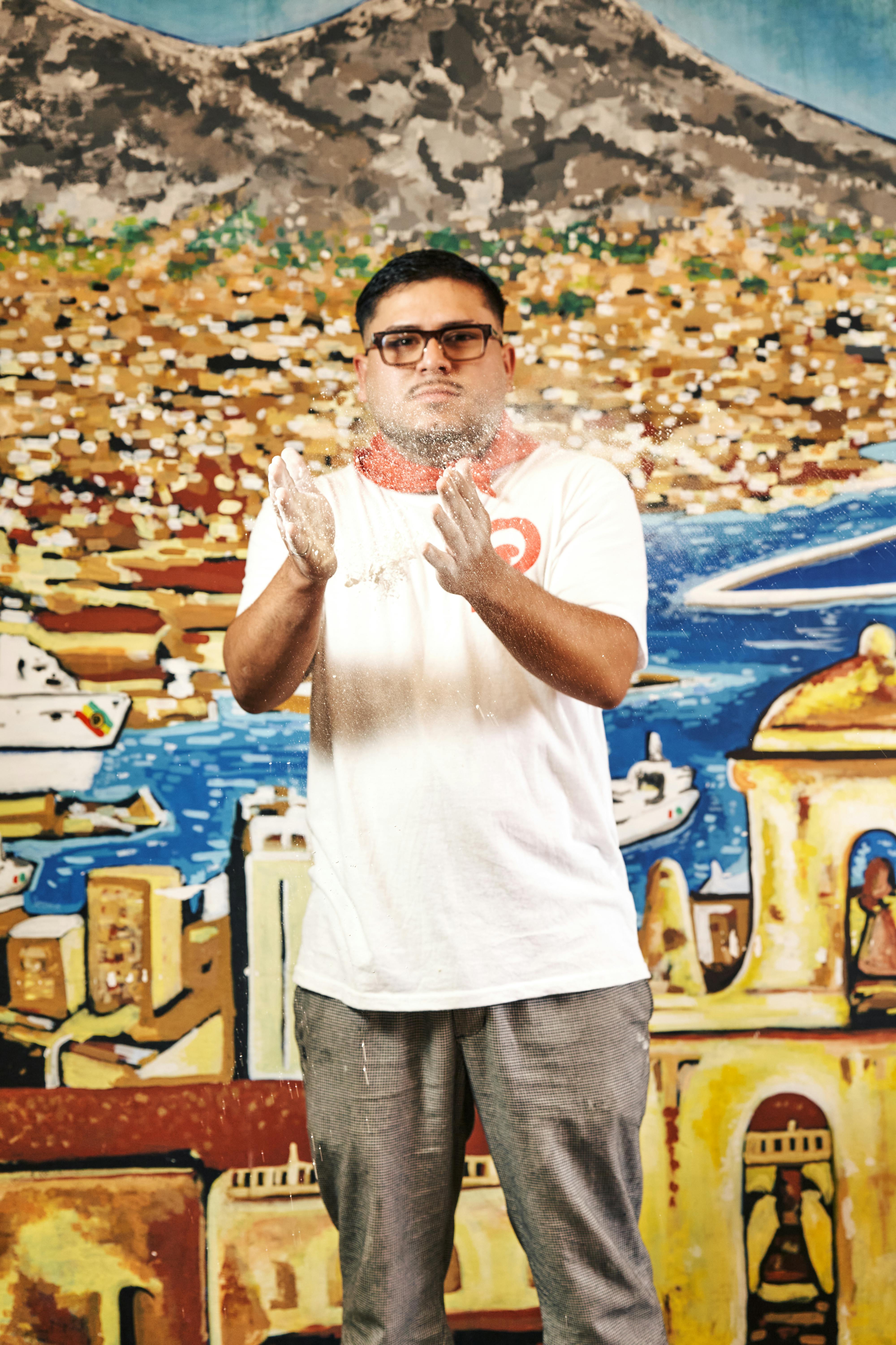 De franc Jove aplaudint farina amb un fons mural de colors que representa un paisatge urbà. Foto d'estoc