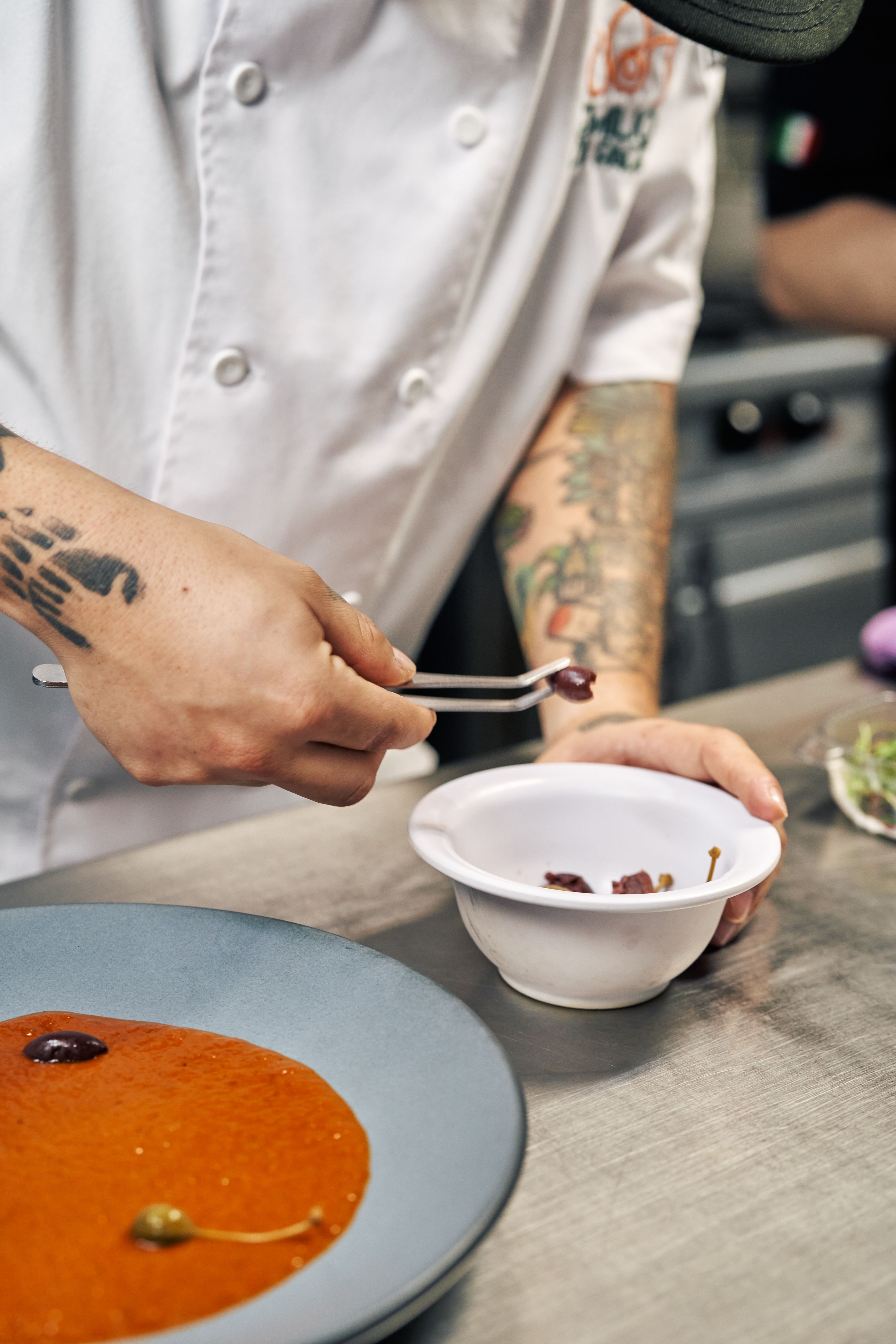 A single dish, meticulously plated — roasted celeriac with wild herbs and fermented sauce, presented on a handmade ceramic plate.