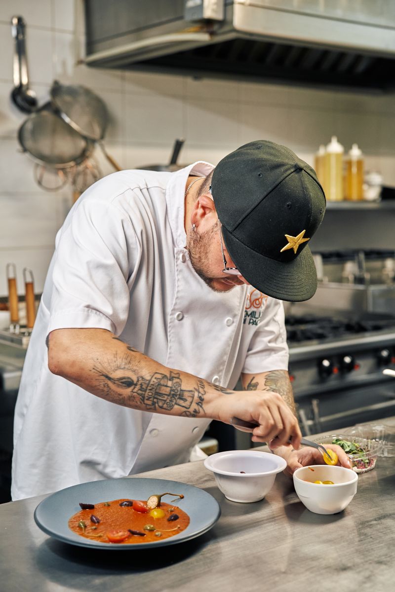 Chef focuses on plating a gourmet dish in a professional kitchen setup.
