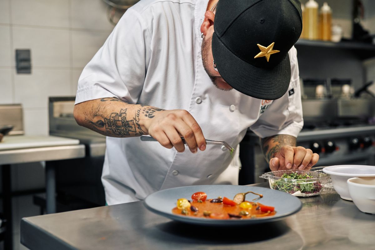 A chef plating a dish while the restaurant chatbot handles reservations
