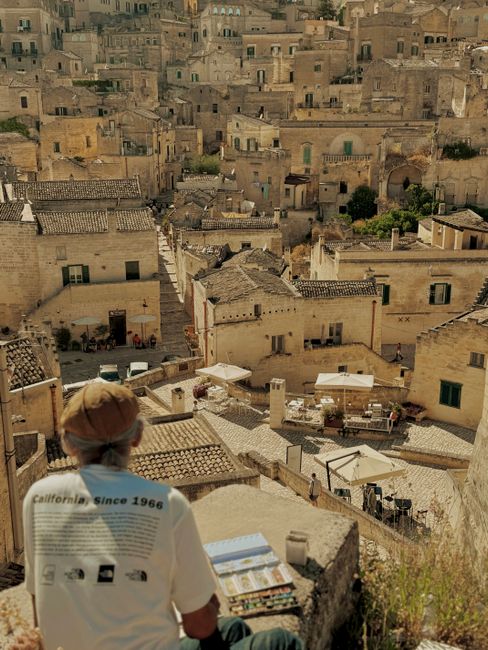 A person overlooks the ancient stone buildings of Matera, Italy, showcasing its historic charm.