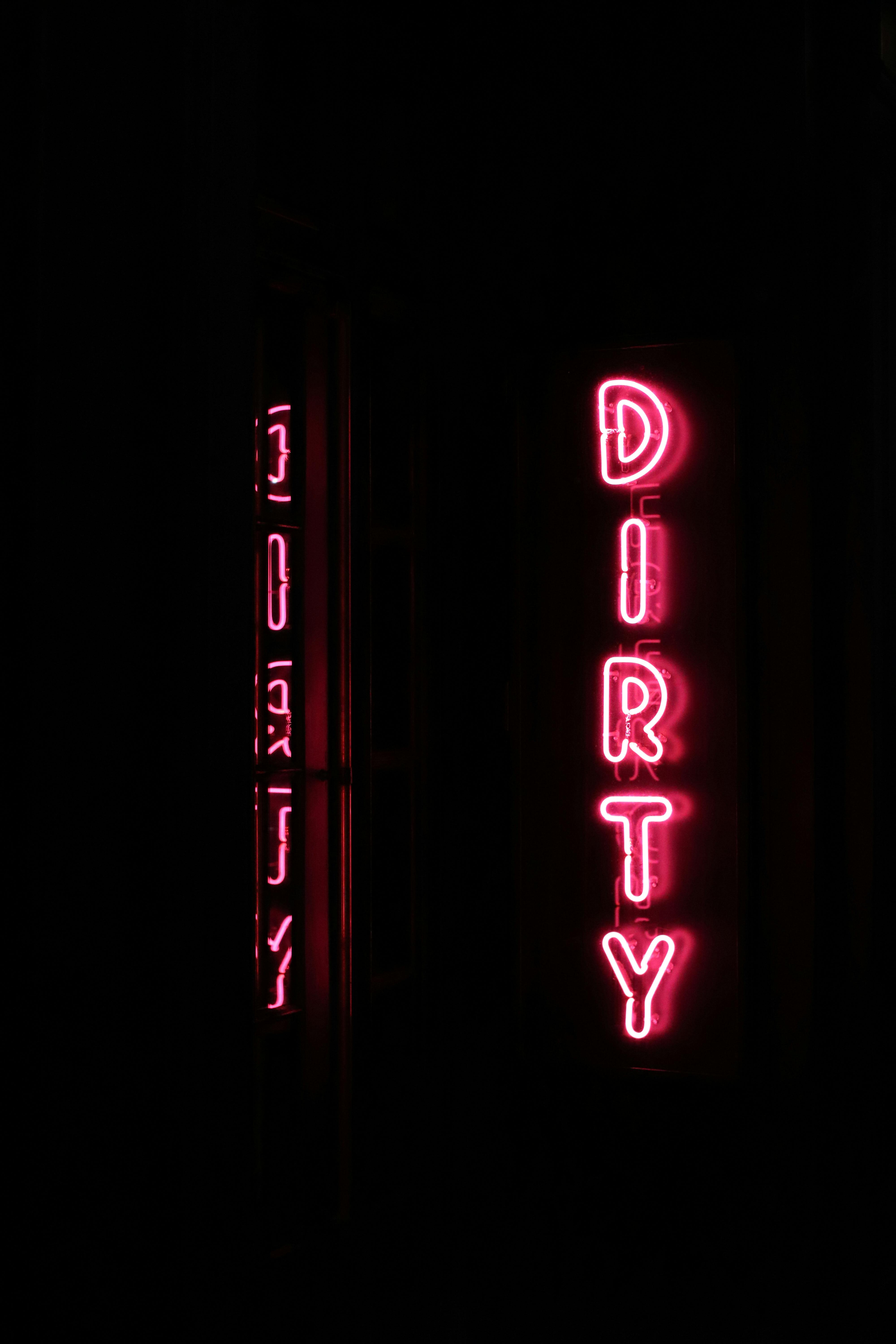 Free Vertical pink neon sign reading 'DIRTY' at night in New York City. Stock Photo