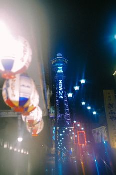 Captivating night view of Tsutenkaku Tower in Osaka, Japan, with colorful lanterns and neon lights.