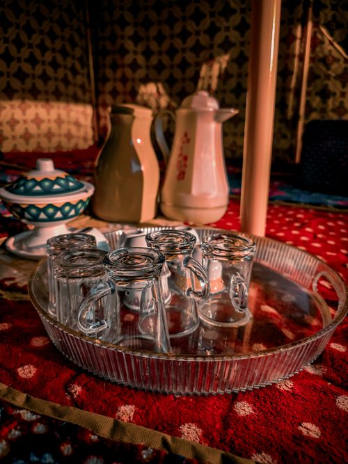 Free A beautifully arranged tea set with glasses and pots on a vibrant red patterned tablecloth. Stock Photo
