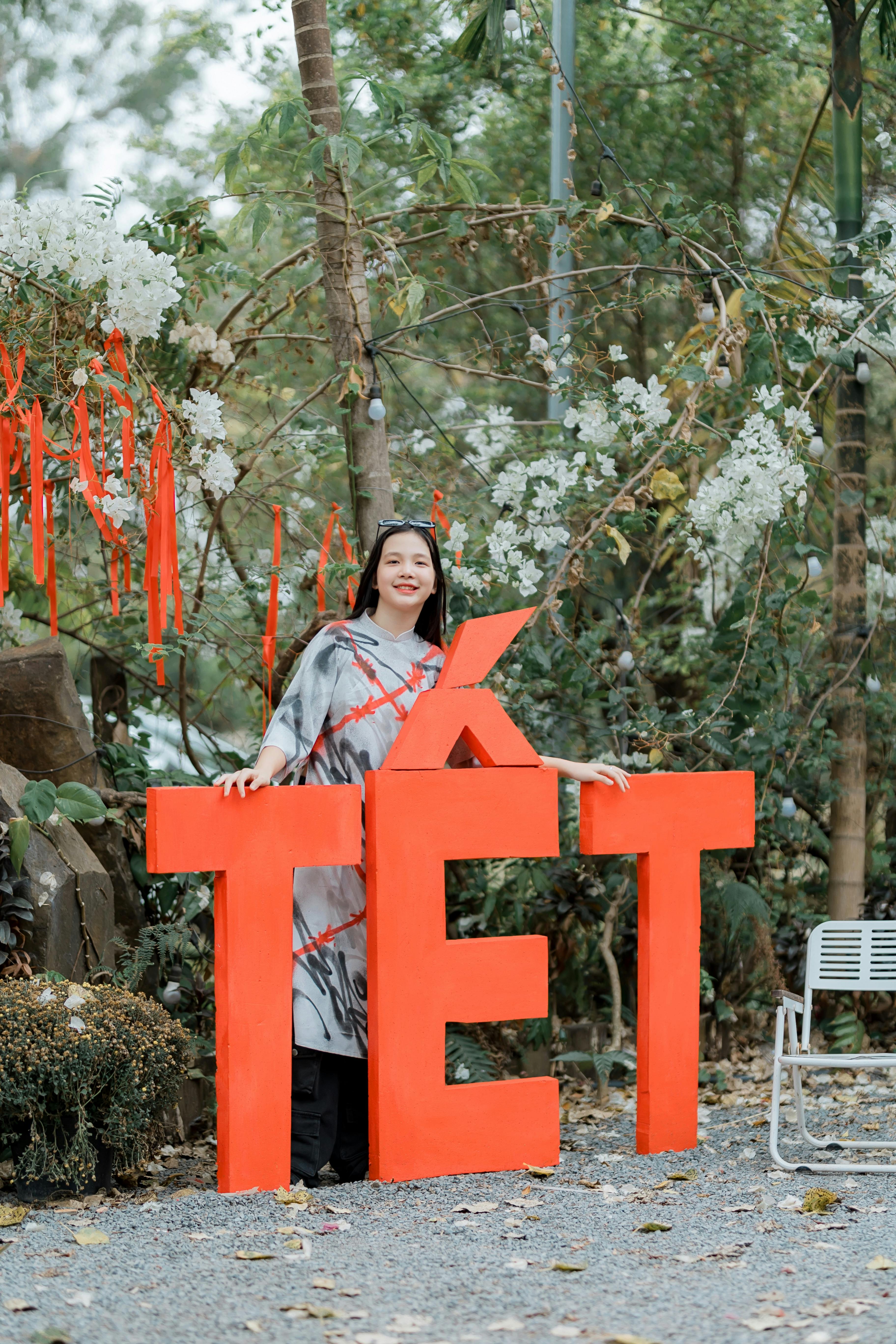 Woman celebrating Tet festival with vibrant decorations and large text.