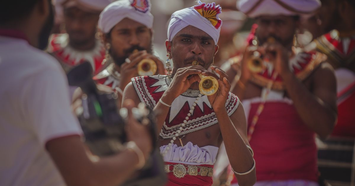 Traditional Sri Lankan musicians playing flutes in a vibrant cultural parade outdoors.