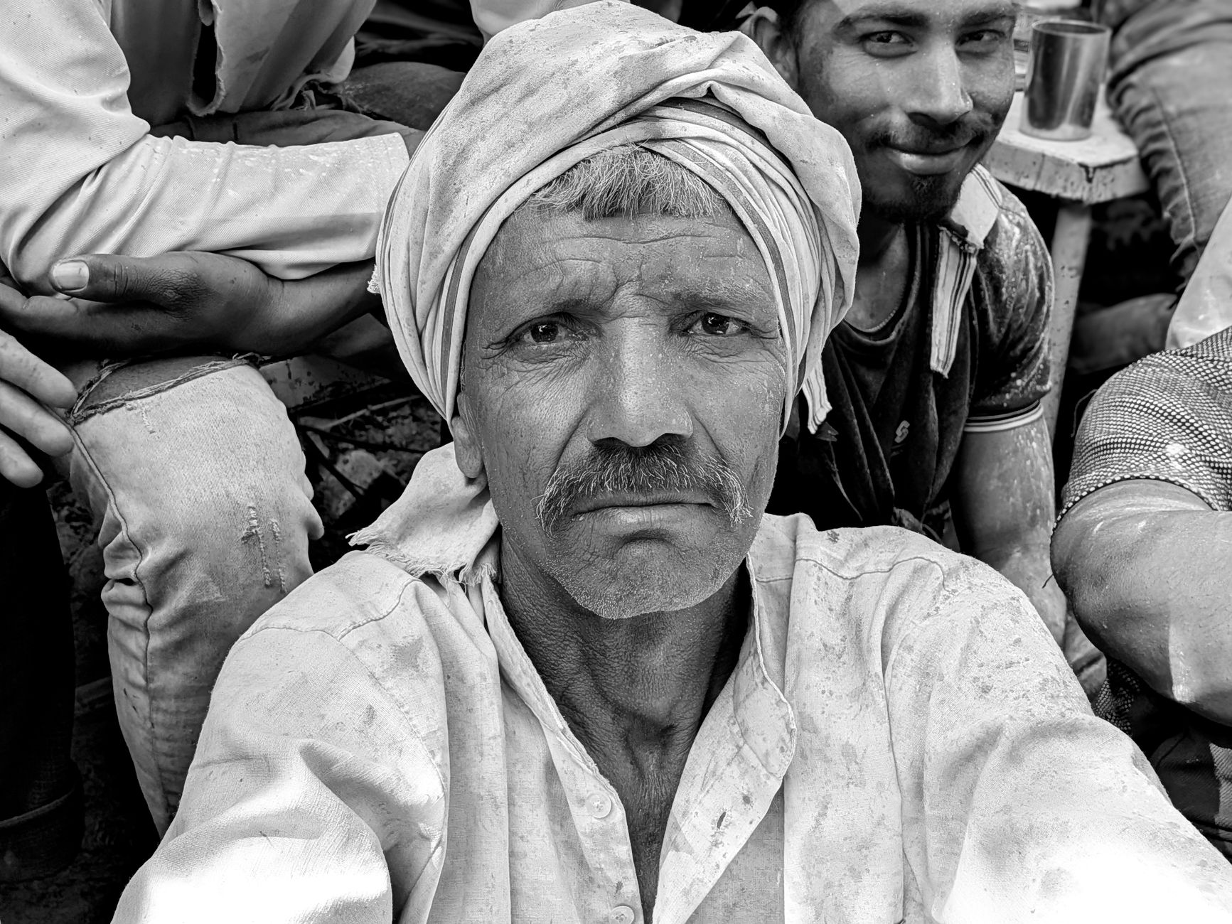 Close-up black and white portrait of an elderly man wearing a turban with a contemplative expression.