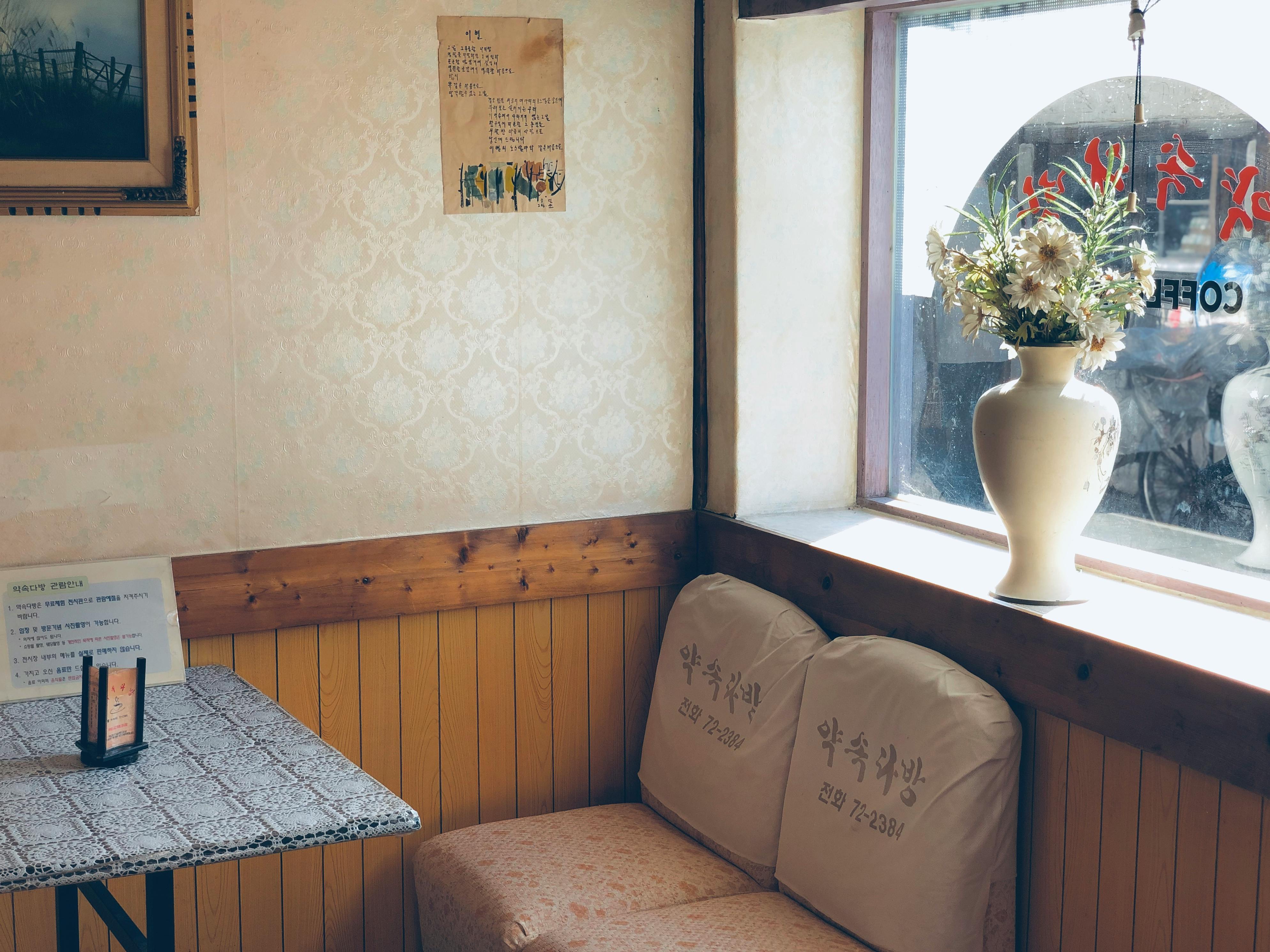 复古咖啡馆的温暖角落里，有座位、阳光和窗前的花瓶