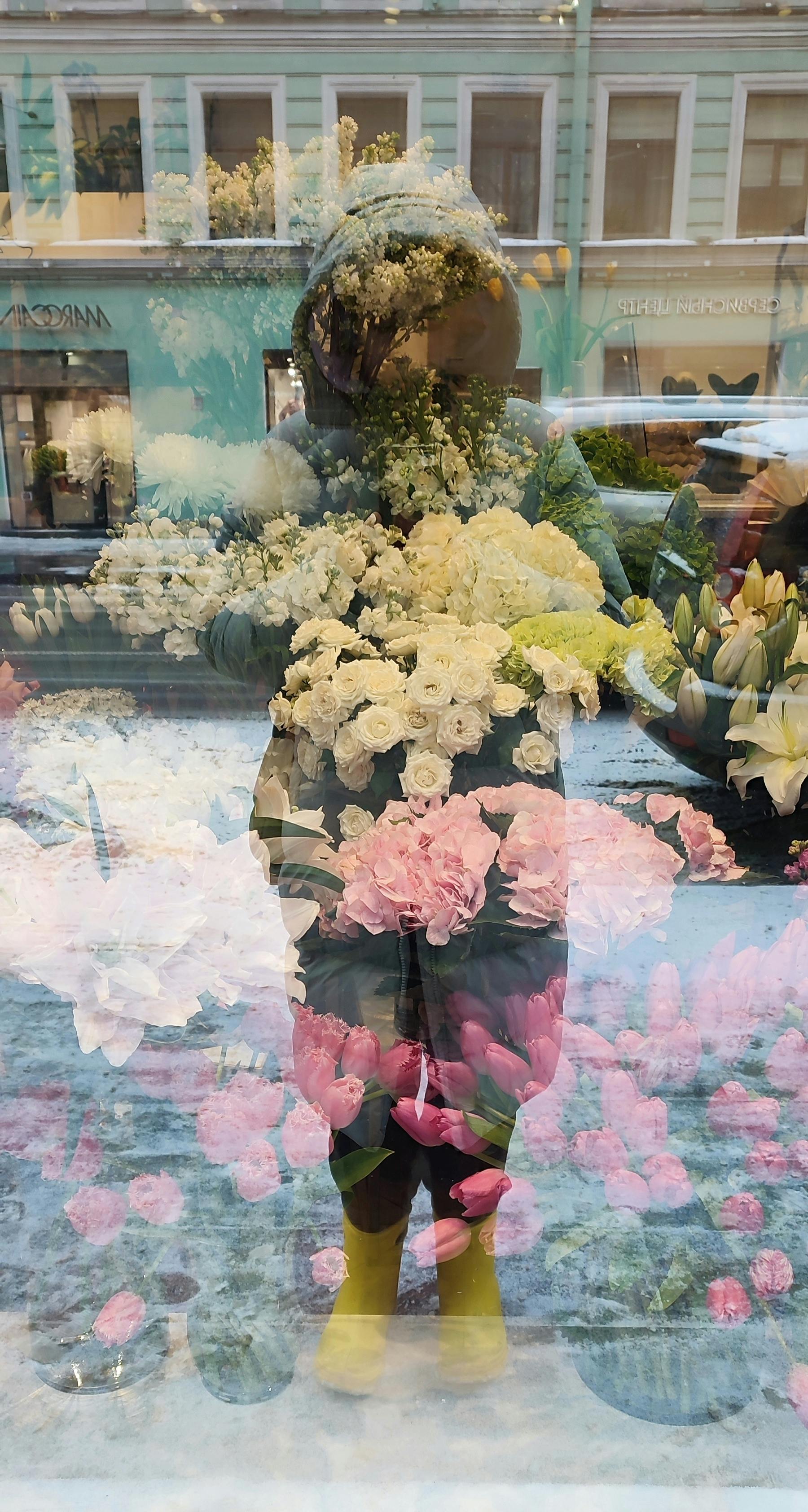 Ücretsiz Kış gününde, yansıtıcı bir dükkan vitrininden yansıyan çiçekler ve sokak manzarasının birleşimi. Stok Fotoğraflar