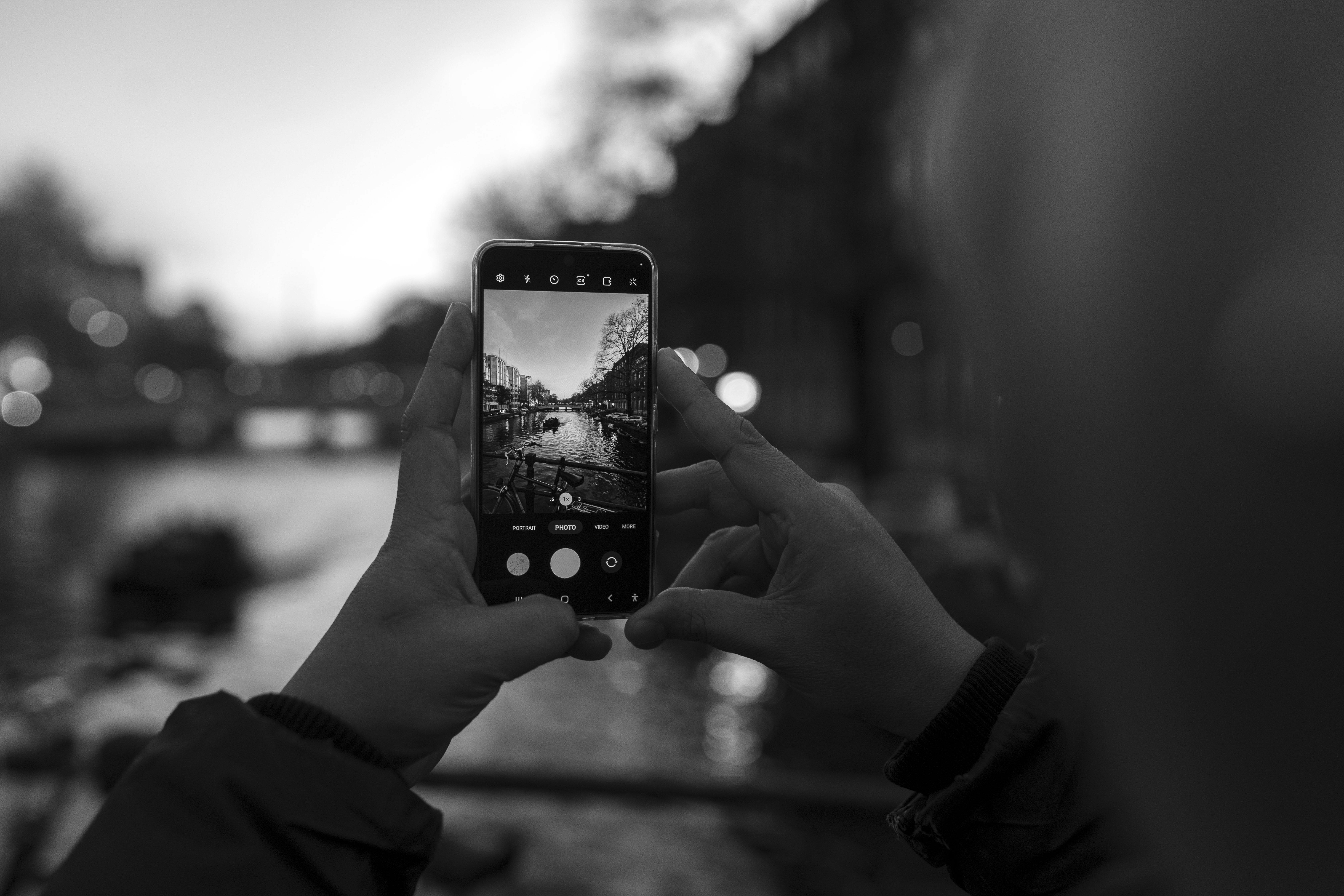 Ücretsiz Bir kişi, Amsterdam'da alacakaranlıkta bir kanal manzarasını akıllı telefonuyla fotoğraflıyor. Stok Fotoğraflar