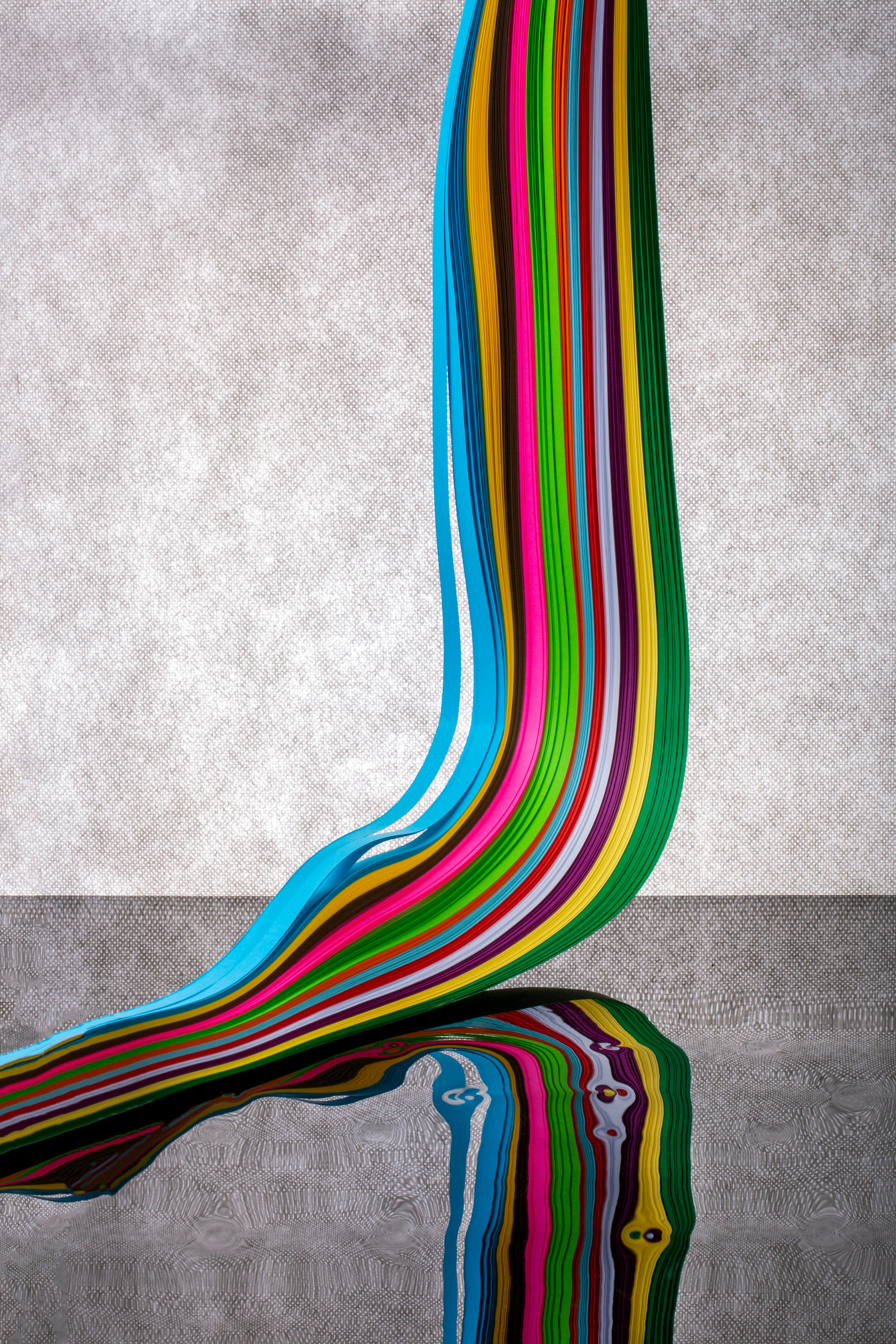 Free A flowing multicolored ribbon creating a colorful abstract pattern on a reflective surface. Stock Photo