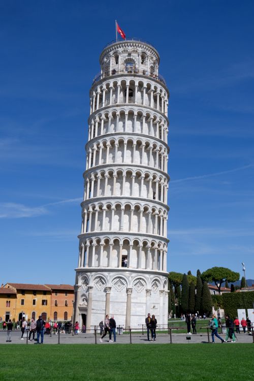 Free The Leaning Tower of Pisa against a clear blue sky with visitors nearby, showcasing its historic charm. Stock Photo