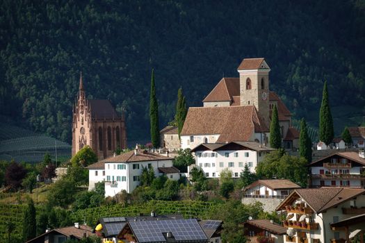 Picturesque view of Schenna village in South Tyrol with its iconic historic church, surrounded by lush greenery.