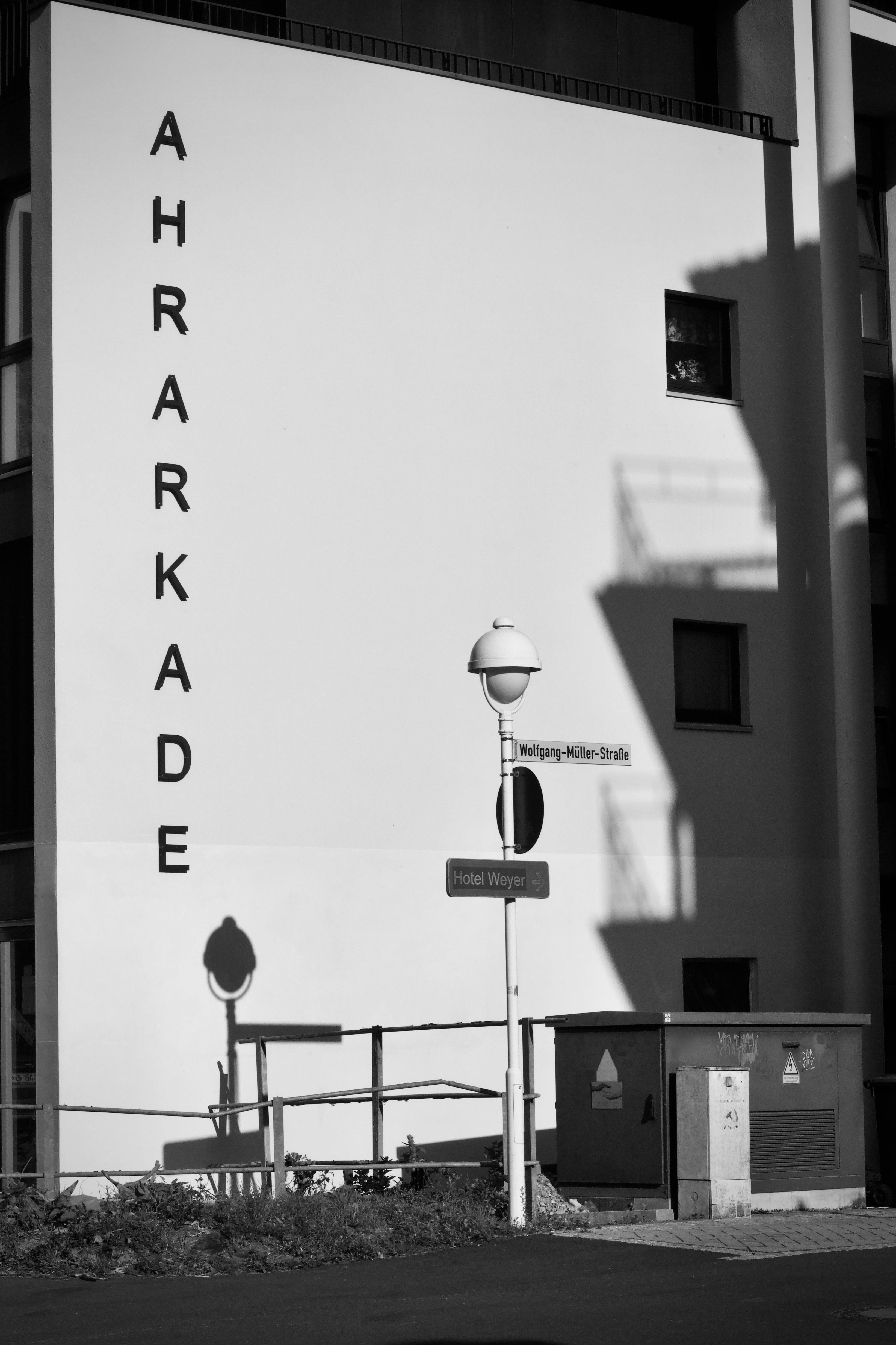 Black and white photo of a modern building facade with signage and street elements.