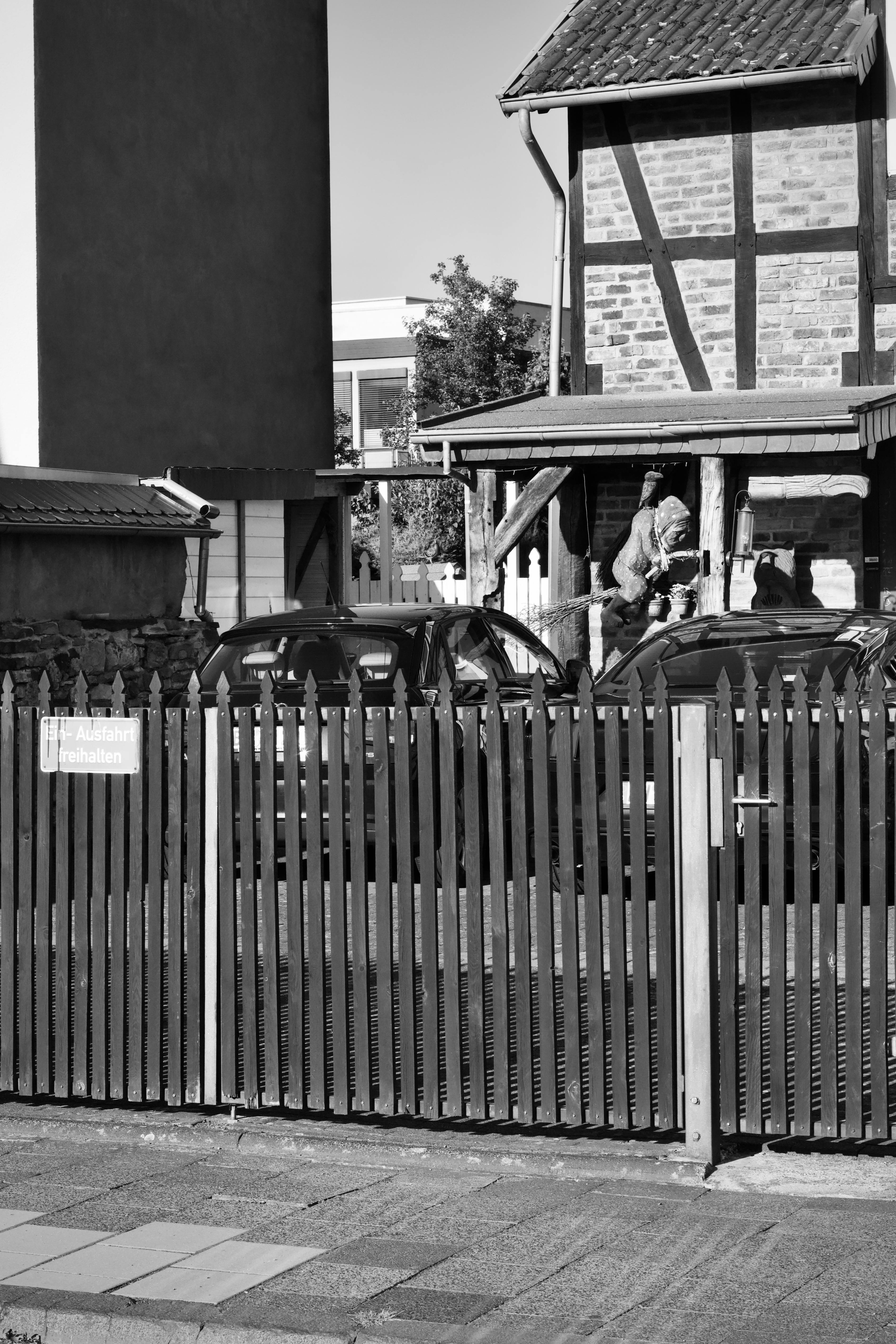 Gratis Monokrom bybillede med biler og en traditionel bygning bag et hegn. Lagerfoto