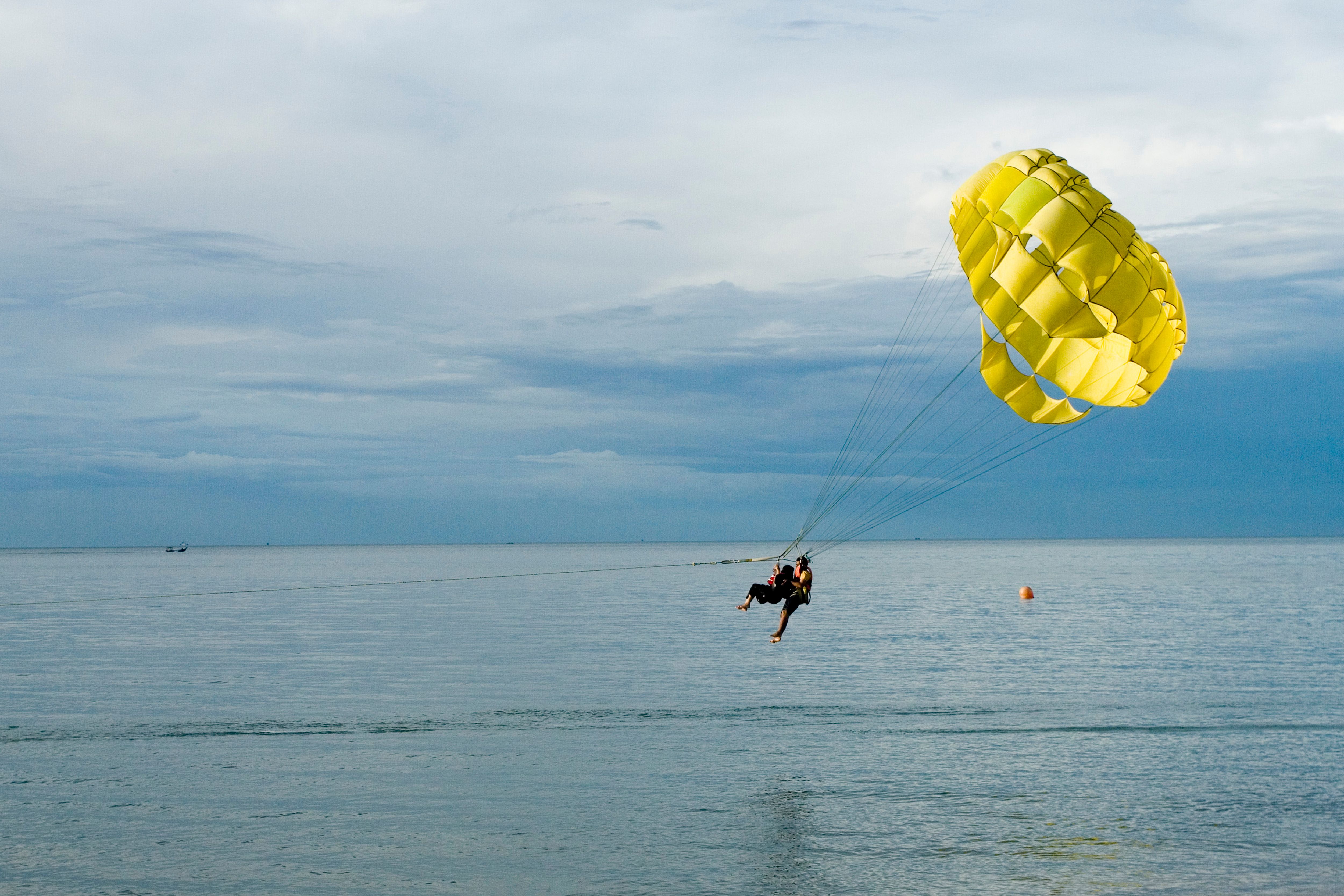 Gratis Un'entusiasmante esperienza di parasailing con paracadute giallo sopra l'oceano tranquillo. Perfetto per gli amanti dell'avventura. Foto a disposizione