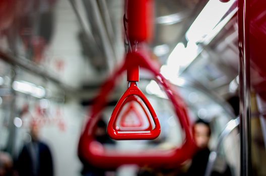Focused shot of a red handrail inside an Istanbul subway during daytime travel.