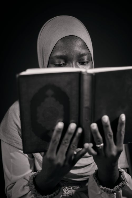 Free A black and white portrait of a woman in a hijab reading a book, focusing on knowledge and culture. Stock Photo