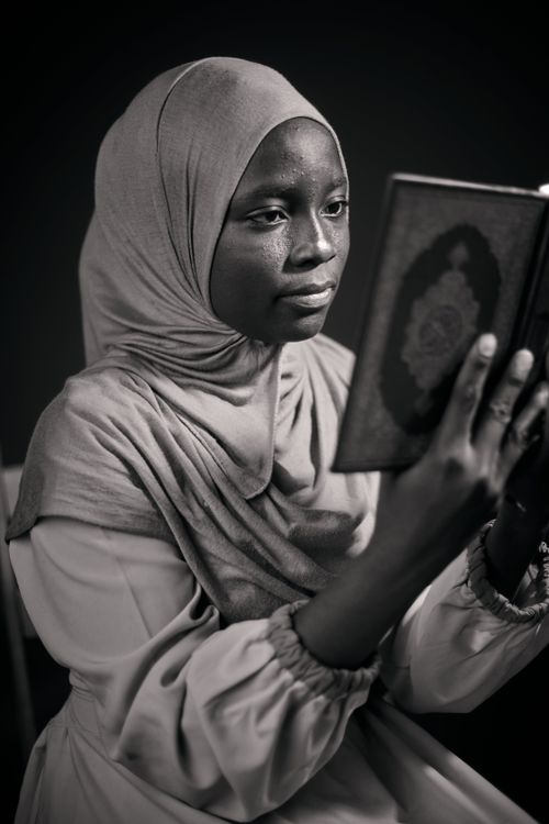 Free A young woman in a hijab attentively reads a book indoors, conveying concentration and contemplation. Stock Photo