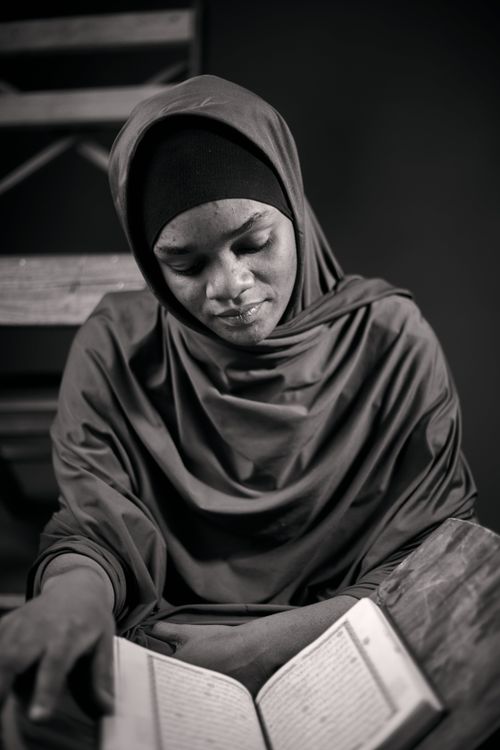 Free Black and white portrait of a young African woman in a hijab reading a book indoors. Stock Photo