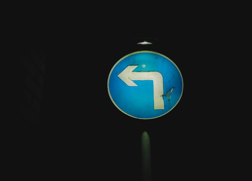 Free Round old left turn sign on blue background with light at dark night Stock Photo