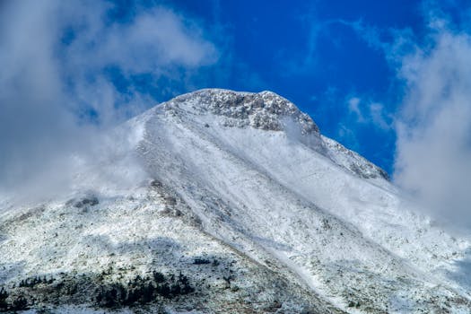 Beautiful snow-covered mountain peak with a vibrant blue sky in Greece.