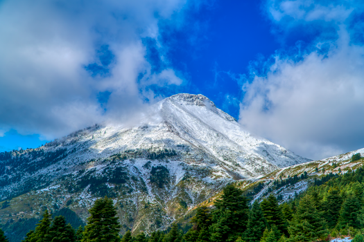 Majestic snowy mountain in Greece under clear blue sky, perfect for nature and travel imagery.