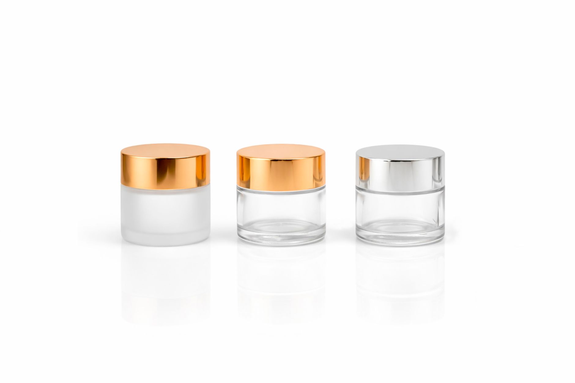 Stylish glass cosmetic jars with metallic lids on a white background, perfect for beauty packaging concepts.