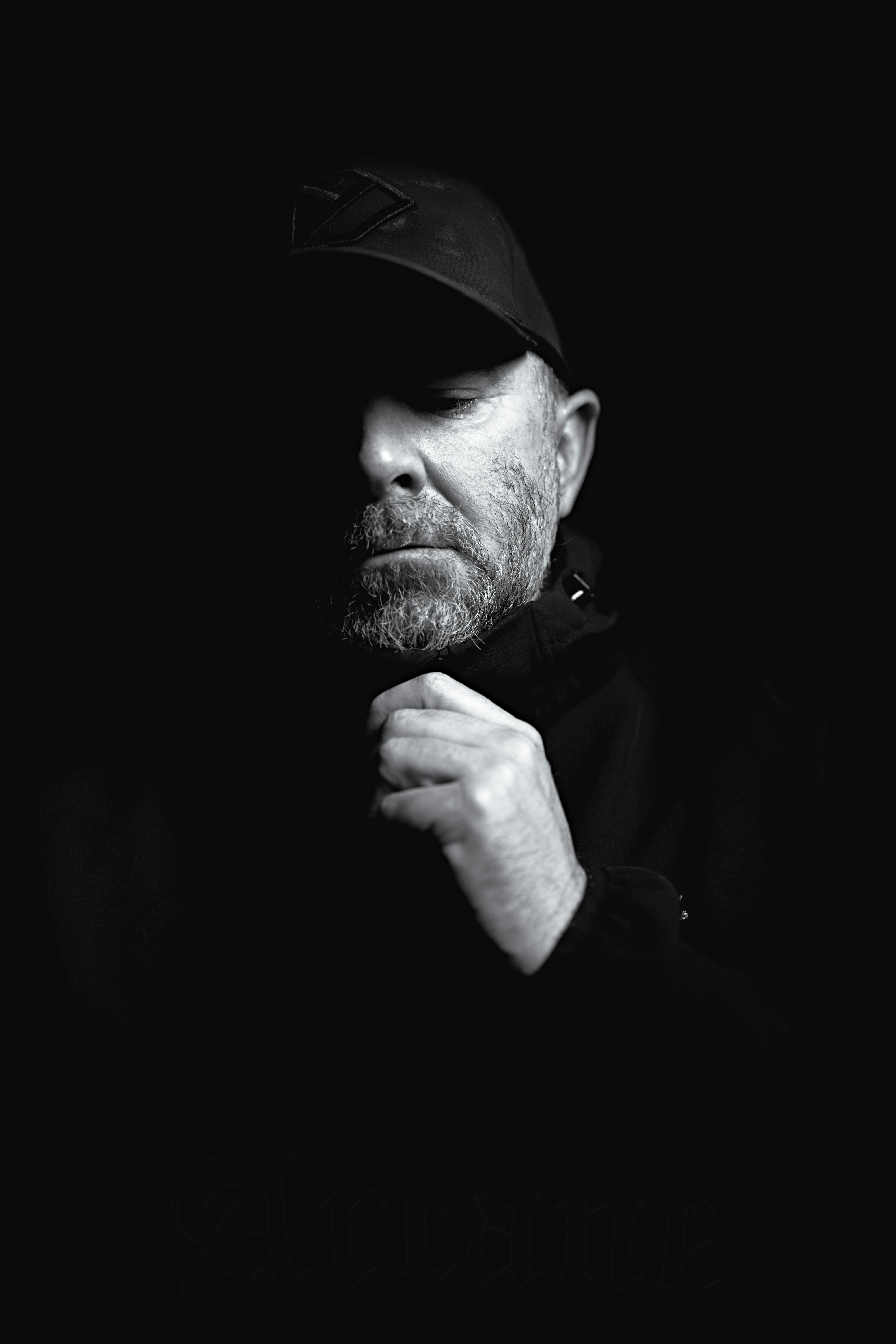 Dramatic black and white portrait of a man in shadow, evoking mystery and introspection.