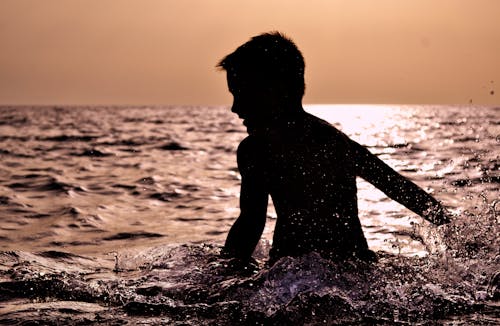Free Silhouette of Boy on Body of Water Stock Photo