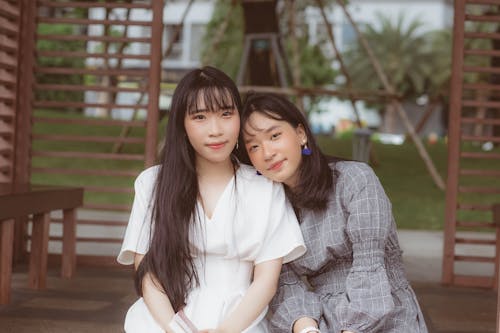 2 Women Smiling Near Brown Wooden Fence