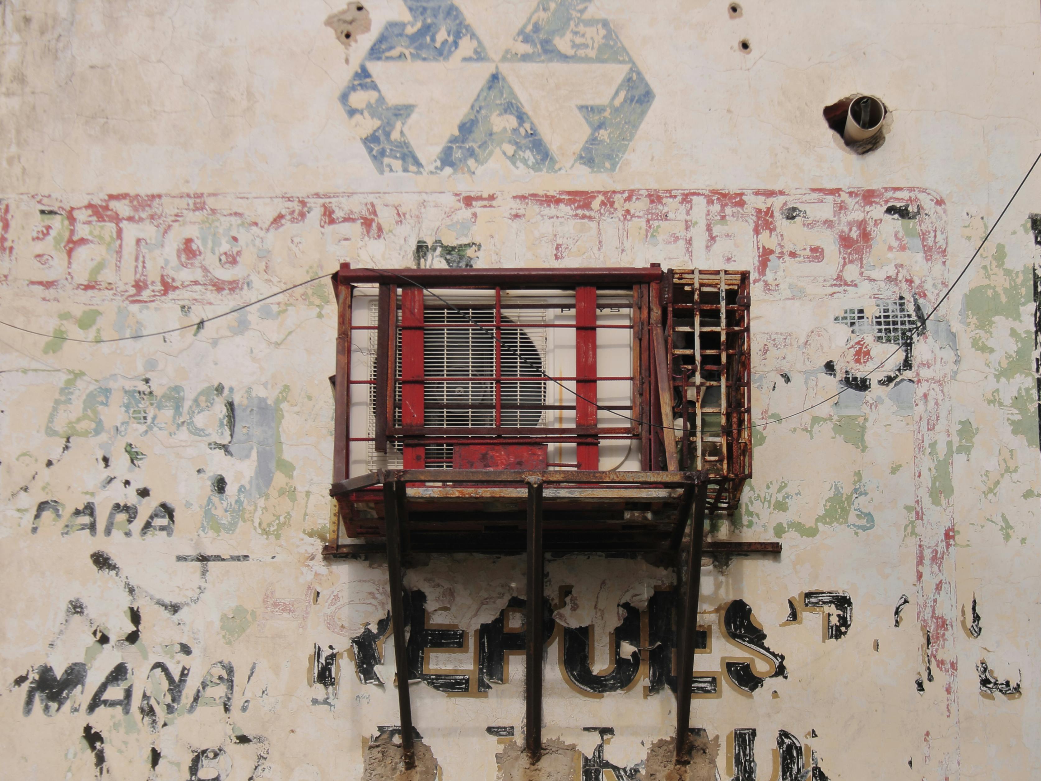 бесплатная Выветренная стена с кондиционером в Маракайбо, демонстрирующая упадок городской среды и уличное искусство. Стоковое фото