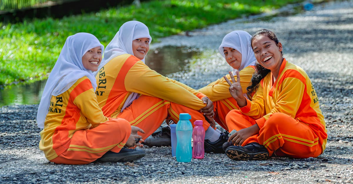 Group of Indonesian female students in traditional sportswear sitting outdoors, smiling.