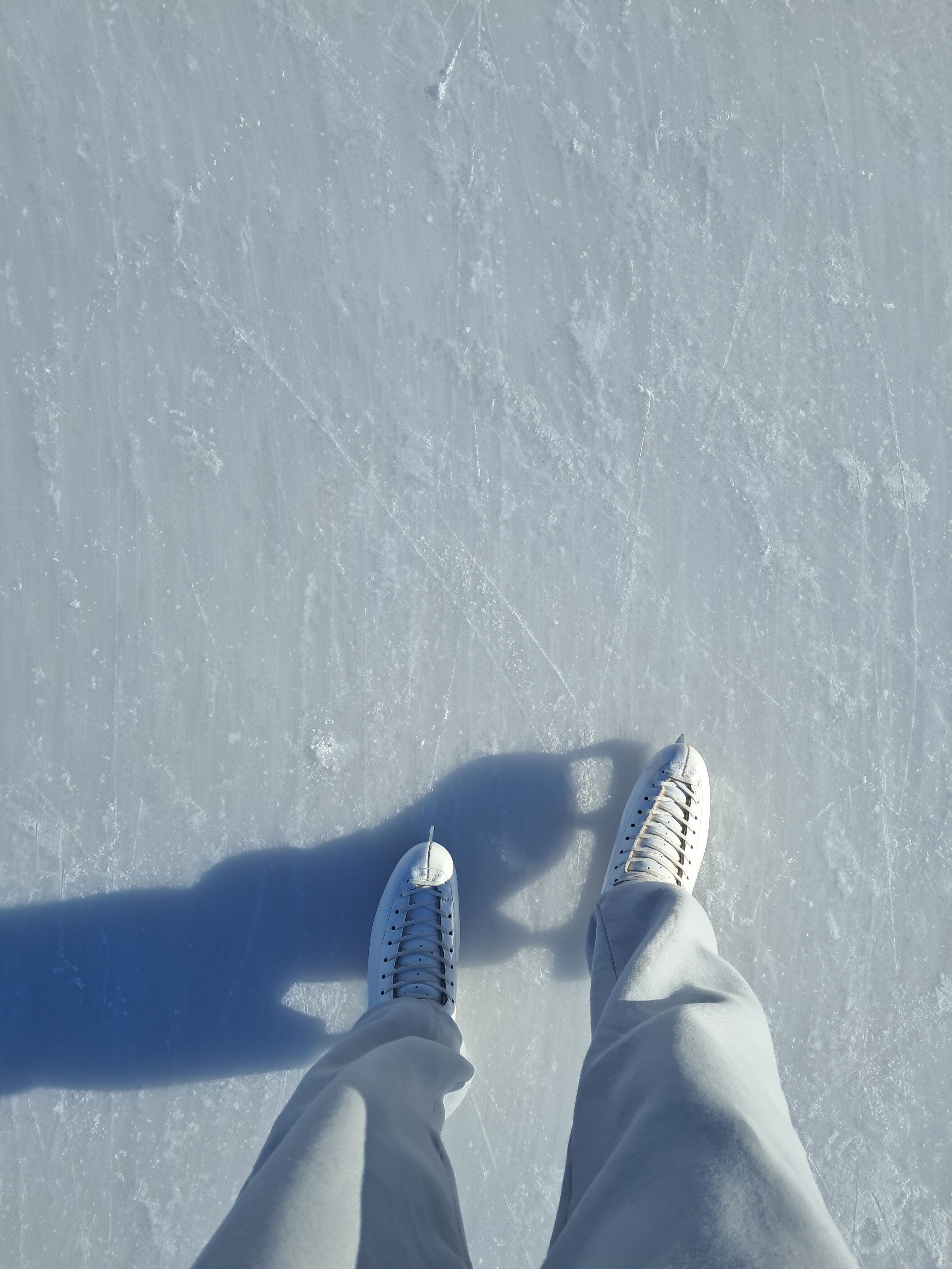 Top view of person ice skating on an outdoor rink showing the ice surface and skates.