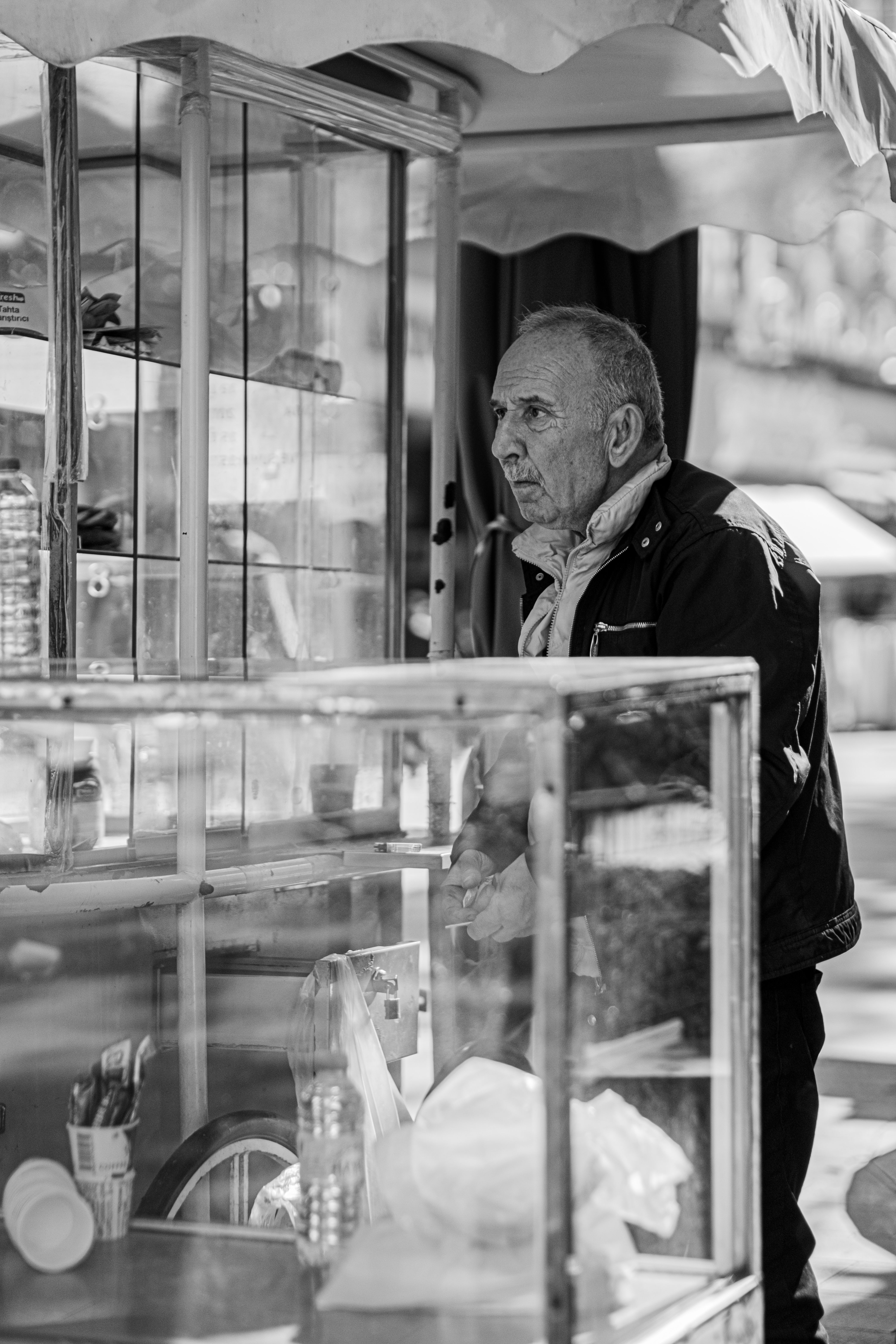 Gratuit Photo en noir et blanc d'un vendeur âgé sur son étal de marché en plein air. Prise sur le vif. Photos