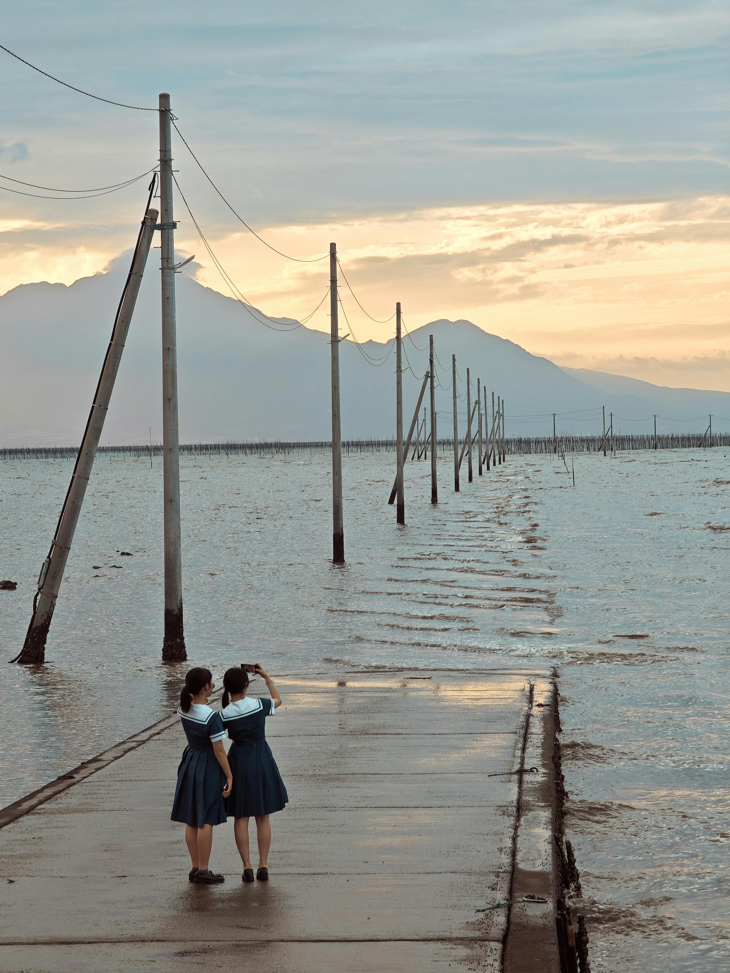 Two girls in school uniforms walking along Uto seashore during a beautiful sunset.