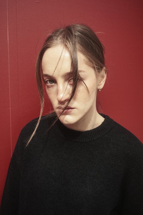 Free Portrait of an adult female in black sweater against a red wall in İstanbul, Türkiye. Stock Photo